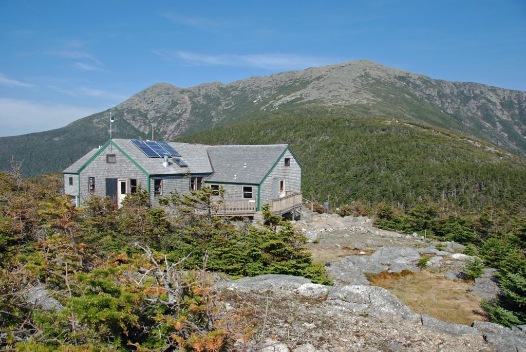 A gray wooden hut set amongst the mountains