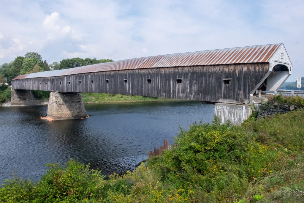 A huge wooden covered bridge spanning a wide river.