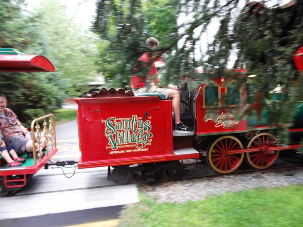 Kids and adults riding on a train labeled "Santa's Village."