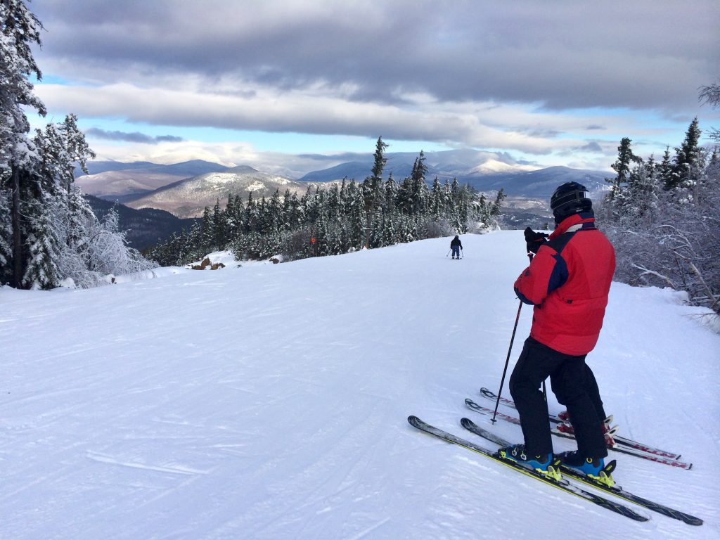 A skier in a red jacket about to head down a hill in New Hampshire.