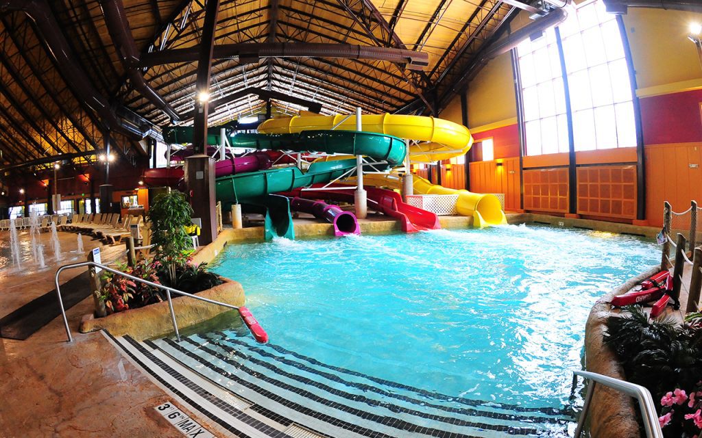 Four colorful water slides leading into an indoor pool at a resort.
