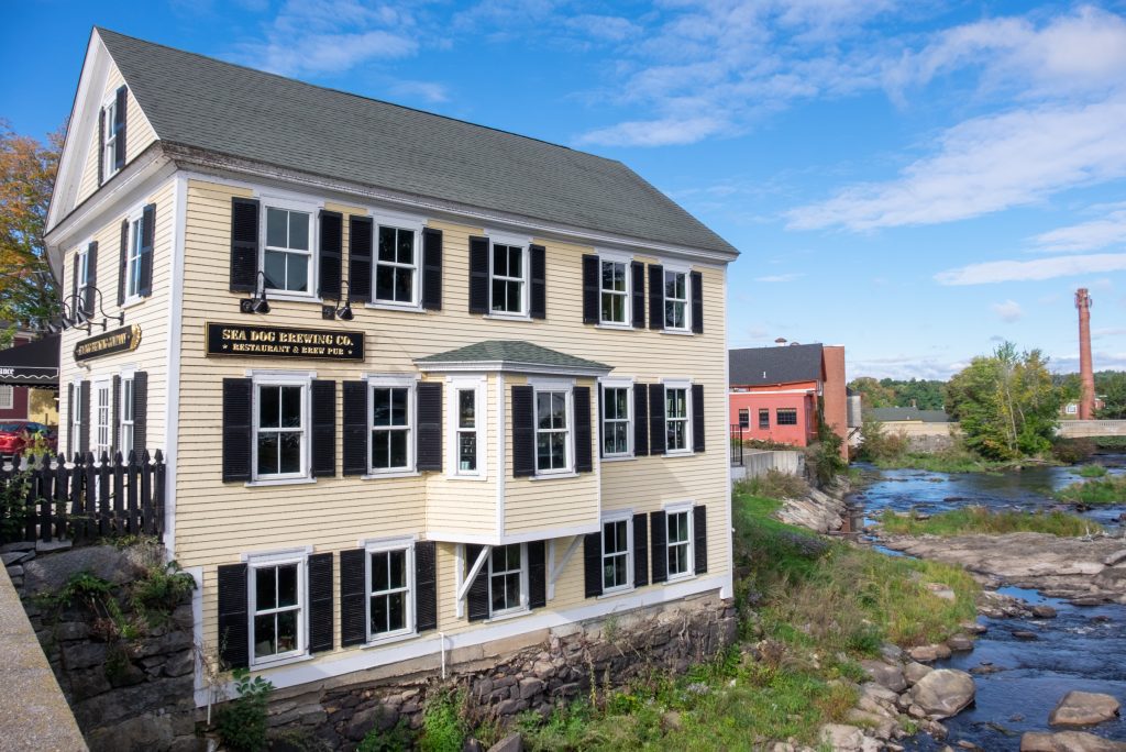 The yellow colonial home reading Sea Dog Brewing Co next to a river in Exeter, NH.