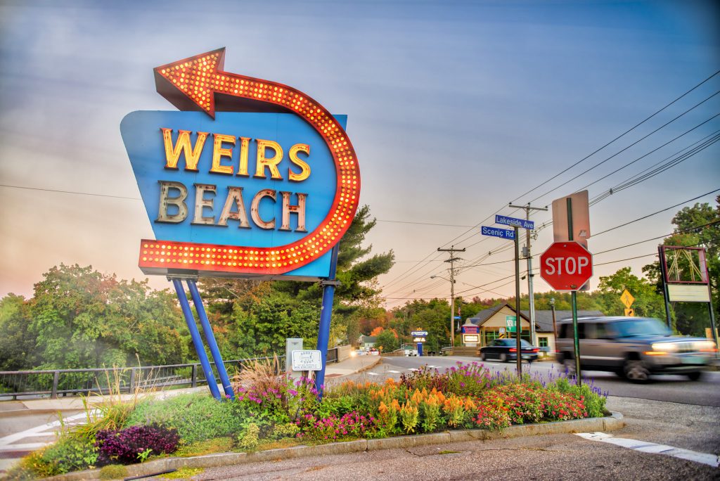 A big lit-up sign that reads WEIRS BEACH with an arrow pointing down the street.