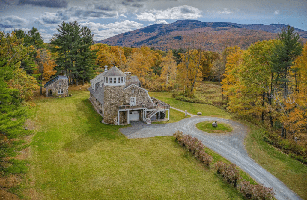 Drone view of a renovated stone barn vacation rental surrounded by fall foliage
