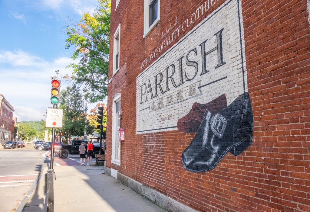 A mural on a brick wall reading Parrish Shoes with two buckled shoes on it.