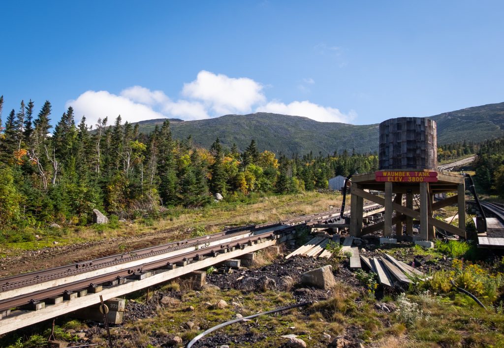 A rail track going through a forest and a tank reading Waumbek Tank Elev. 3800.
