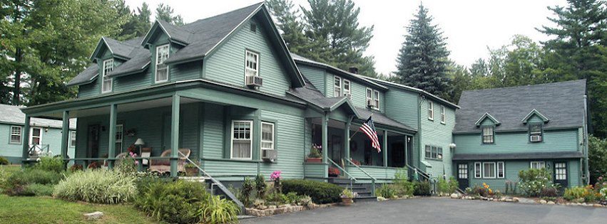 A sprawling mint green home with a gray roof