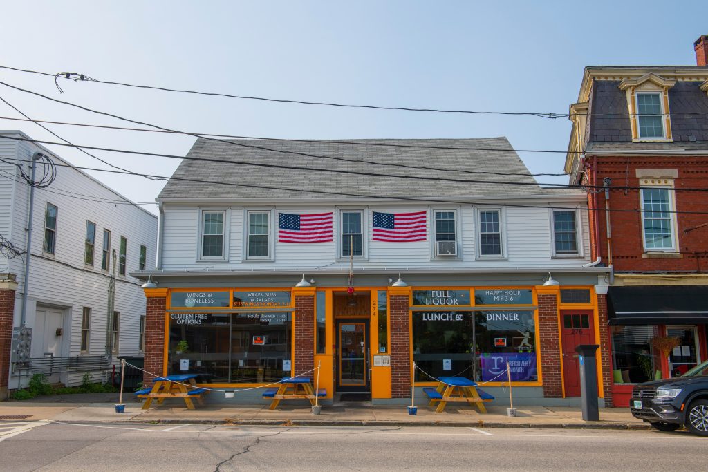 A restaurant on a busy street, two American flags hanging across the top floor.