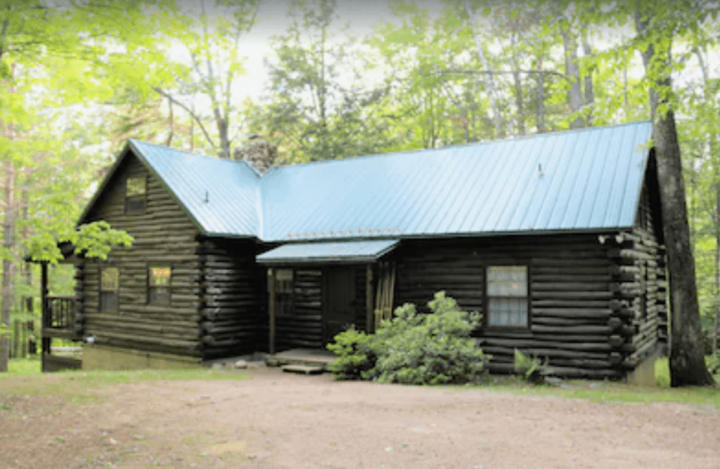 A log cabin with green trees behind it