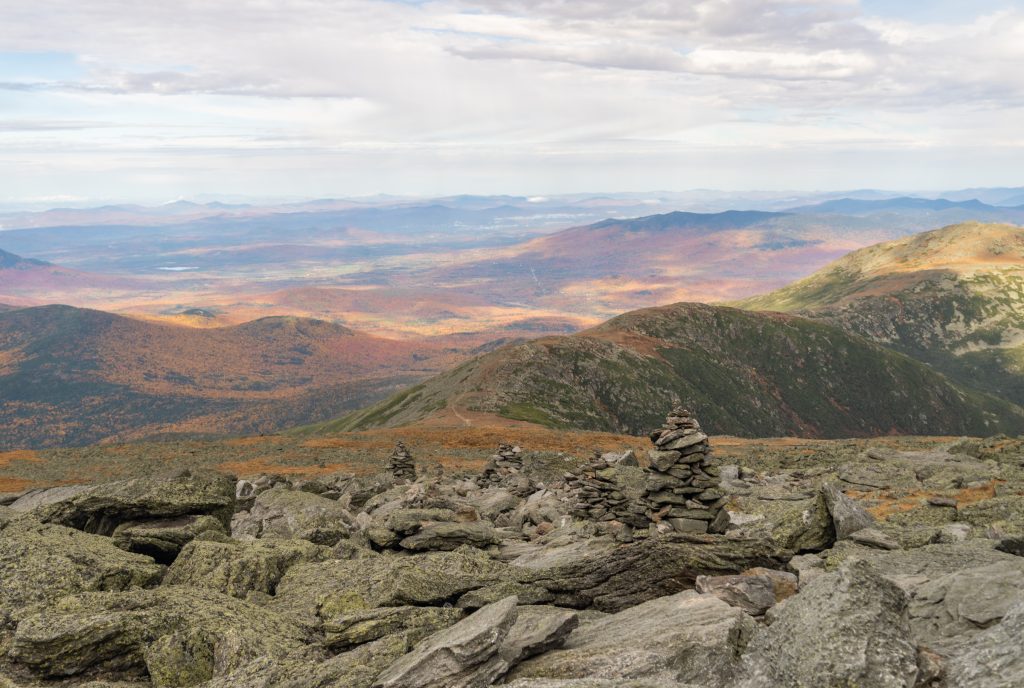 An overview with a rocky pass leading to mountains covered with yellow and orange trees.