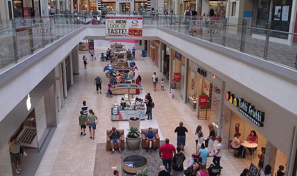 People walking through a retro-looking beige shopping mall.