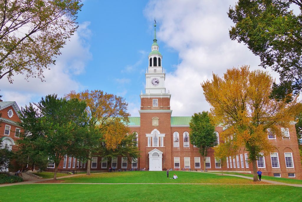 A brick building at Dartmouth College with a tall white tower in the middle, surrounded by trees.