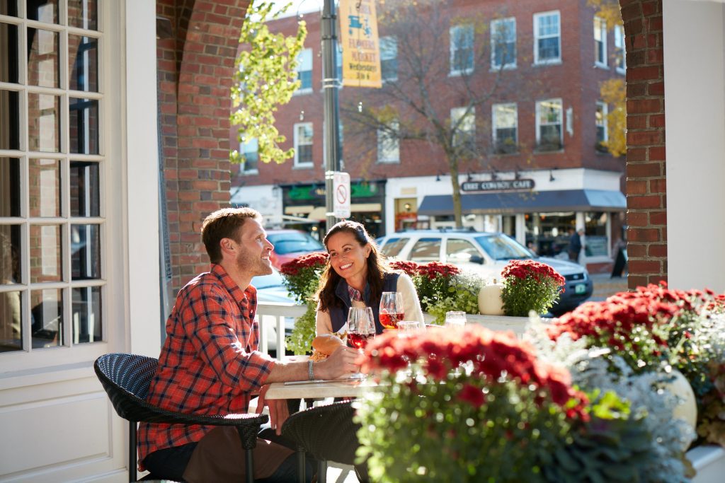 A couple enjoying glasses of wine while sitting out doors on Main Street in Hanover in front of brick buildings.