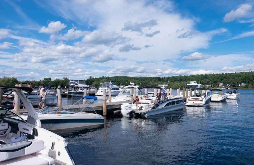 Dozens of white speedboats moored on a wooden pier on a lake.