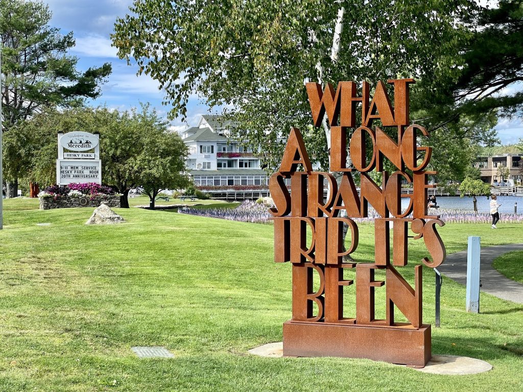A metal sculpture on a lawn reading What a Long Strange Trip It's Been.