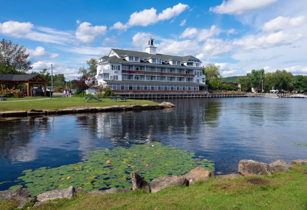A big white hotel perched on the calm edge of a lake.